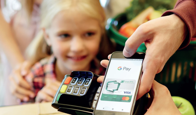 Obrazek dekoracyjny: płacenie za zakupy w sklepie telefonem za pomocą aplikacji Google Pay