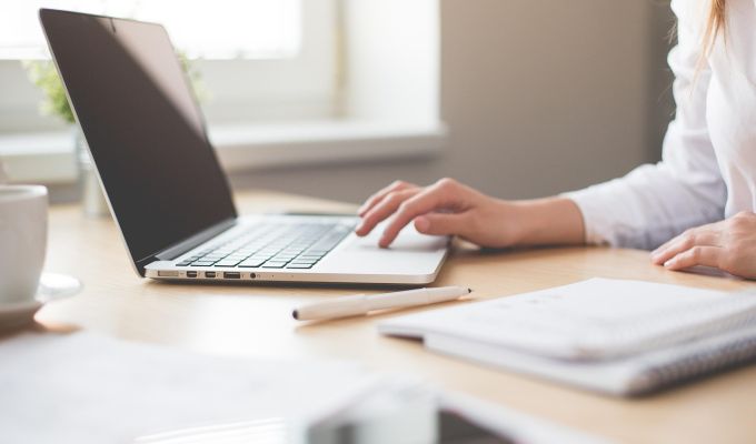 Obrazek dekoracyjny: Osoba pracująca przy laptopie w komfortowym biurze, ilustrująca dostępność cyfrową i nowoczesne podejście do pracy z technologią