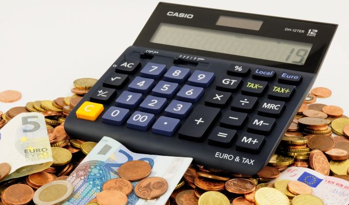 Obrazek dekoracyjny: kalkulator leży na drobnych monetach